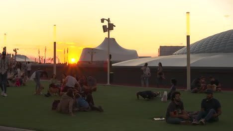 Gente-Al-Aire-Libre,-Viendo-La-Puesta-De-Sol-Sentada-En-Un-Césped