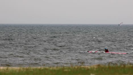 Wind-Surfer-Approaches-Beach-and-Falls-into-Water-with-Sail-in-Pattaya,-Thailand