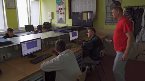 Teacher-Checking-Work-Done-By-Computer-And-IT-Student-In-A-Trade-High-School