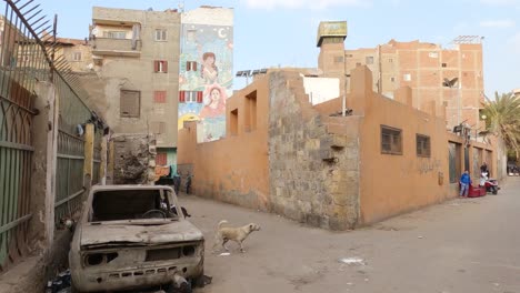 Poor-environment-in-Old-Cairo,-Abandoned-Car,-decay-buildings-and-kids-playing-in-the-street,-Egypt