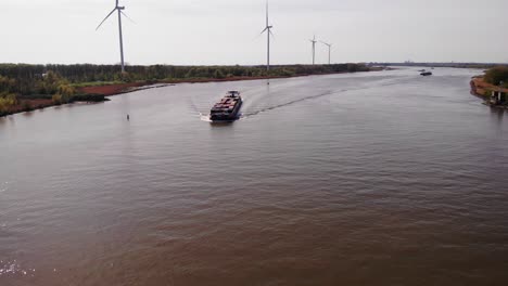 Luftaufnahme-über-Oude-Maas-Mit-Dem-Sich-Nähernden-Frachtschiff-Petran-Mit-Windmühlen-Im-Hintergrund