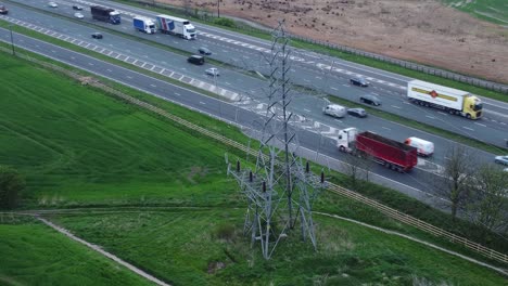 Fahrzeuge-Auf-Der-Autobahn-M62,-Vorbei-Am-Pylonturm-Auf-Landwirtschaftlichen-Feldern,-Luftaufnahme,-Abstieg-Aus-Hohem-Winkel