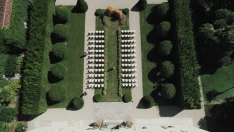 Volando-Hacia-Atrás-Sobre-El-Techo-Frente-Al-Patio-Trasero-Sentado-Para-Una-Boda-En-La-Famosa-Villa-Balbiano-Inclinándose-Hacia-Arriba-Revelando-El-Lago-Como-Con-Botes-Y-Montañas-Alpinas