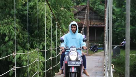 suspension-bridge-over-the-river-with-motorcycle-crossing-on-it-in-the-morning-in-Sukabumi,-west-java,-Indonesia-on-May-4,-2022