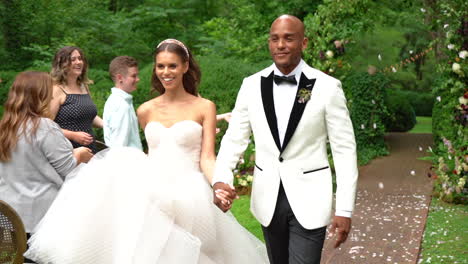 Beautiful-African-American-bride-and-groom-walking-down-the-aisle-just-after-getting-married-on-their-wedding-day-with-guests-throwing-flower-petals-in-the-air-in-slow-motion