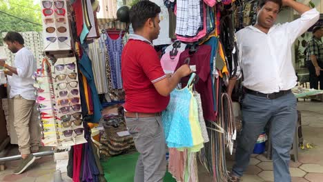 Un-Tendero-Arregla-Las-Prendas-En-Un-Mercado-Local-De-Prendas-De-Vestir