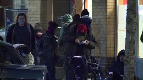 Grupo-De-Personas-Sin-Hogar-Comiendo-Afuera-En-La-Calle