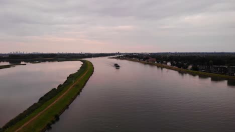 Aerial-View-Over-River-Noord-With-Empty-Inland-Cargo-Ship-Rosanne-Approaching-In-Distance