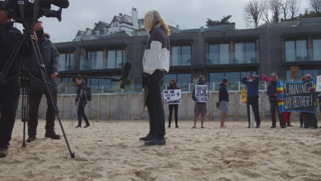 Mujer-Activista-Entrevistada-Por-El-Equipo-De-Televisión-Frente-A-La-Playa-En-El-Hotel-Carbis-Bay,-Cornwall.