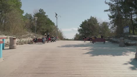 People-Families-and-Elder-Sitting-on-Benches-near-Palanga-Bridge-on-Sunny-Afternoon