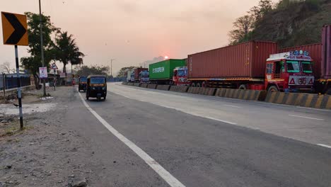 Rickshaw-Automático-Indio-Que-Rompe-Las-Normas-De-Tráfico,-Conduce-Por-El-Camino-Equivocado-En-La-Carretera-Con-Mucho-Tráfico-En-Un-Lado-De-La-Carretera-India-Con-Grandes-Camiones,-Contenedores,-Grandes-Vehículos-Con-Mercancías