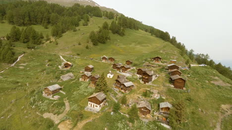 Athletes-Passing-By-A-Small-Village-And-Green-Forest-During-Raid-Evolènard-2021-Race,-In-Valais,-Switzerland