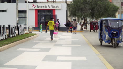 people-passing-by-near-Main-Square,-Ascope,-La-Libertad,-Peru