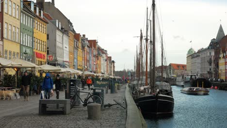 Menschen,-Die-An-Der-Promenade-Des-Nyhavn-Kanals-In-Kopenhagen,-Dänemark,-Mit-Farbenfrohen-Gebäuden-Am-Wasser-Und-Alten-Schiffen-Spazieren