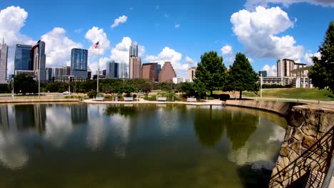 Ein-Langsamer,-Sanfter-Schwung-Aus-Weißen,-Bauschigen-Wolken-Und-Die-Skyline-Von-Austin,-Die-Sich-Im-Palmer-Pond-Spiegelt