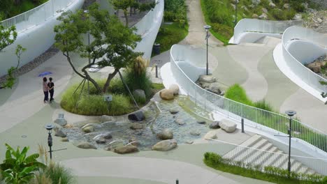 Korean-Women-With-Umbrella-Walking-Near-The-Fountain-At-Geoje-Belvedere-Hotel,-Hanwha-Resort-In-Geoje,-Korea-In-Summer