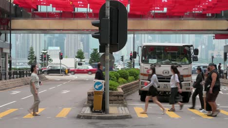 Imágenes-Inclinadas-De-Peatones-Caminando-A-Través-De-Un-Paso-De-Cebra-Mientras-Cientos-De-Banderas-Nacionales-De-China-Y-El-Sar-De-Hong-Kong-Se-Ven-Sobre-Ellos-Durante-El-Aniversario-De-La-Entrega-De-Hong-Kong-A-China