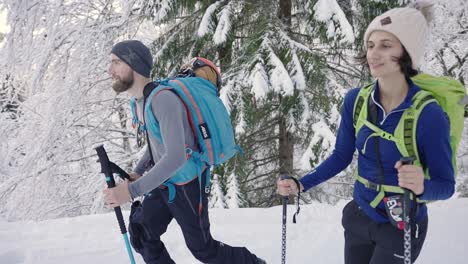 Happy-couple-of-skiers-hiking-with-poles-in-snow-landscape