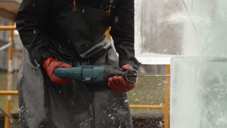 Sculptor-cutting-through-ice-block-with-reciprocating-saw,-Slow-Motion