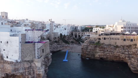 Playa-Cerca-Del-Viejo-Puente-Romano-En-Polignano-A-Mare,-Escenario-Para-La-Competencia-De-Buceo-En-Acantilados-Red-Bull-2021,-Retirada-Aérea-De-Drones