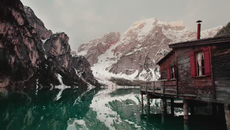 Cabaña-De-Madera-En-Un-Lago-Turquesa-Rodeado-De-Montañas