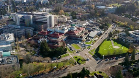 Drone-Reveal-of-Children's-Hospital-and-healthcare-research-campus-with-helipad-in-Vancouver-British-Columbia-Canada,-UHD-aerial-tilt-up-establishing-shot-on-a-sunny-day