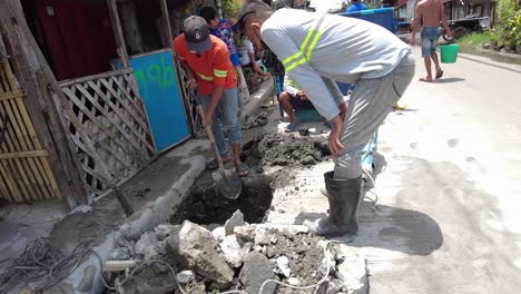 Foremen-wearing-safety-reflective-vests-used-their-shovel,-mixed-cement,-and-demolition-hammer-to-perform-excavation-beside-the-road-gutter-to-install-new-water-piping-from-the-main-water-line