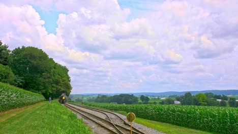 Una-Vista-De-Un-Antiguo-Tren-De-Vapor-De-Pasajeros-Que-Pasa-A-Través-De-Campos-De-Maíz-Que-Soplan-Humo-En-Un-Día-De-Verano