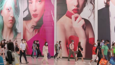 Grandes-Multitudes-De-Personas-Se-Ven-Pasando-Por-Un-Gran-Anuncio-Comercial-En-La-Estación-De-Metro-De-Hong-Kong-Mtr-Temprano-En-La-Mañana-En-El-Distrito-Central,-Hong-Kong