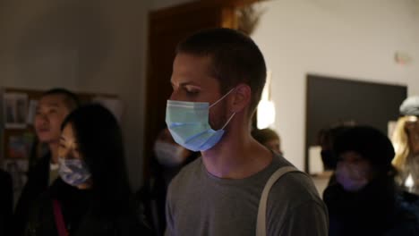 Medium-close-up-of-Caucasian-guy-wearing-face-mask-while-dancing-and-bopping-head-during-live-DJ-music-performance