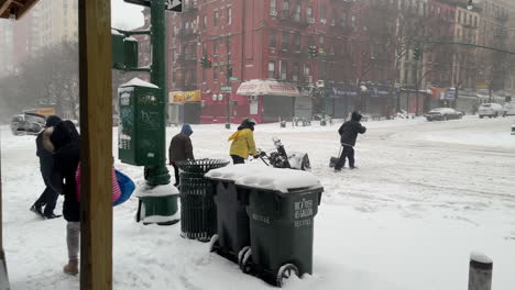 Los-Hombres-Cruzan-La-Calle-Con-Palas-De-Nieve-Y-Soplador-De-Nieve-En-La-Ventisca-De-La-Ciudad-De-Nueva-York