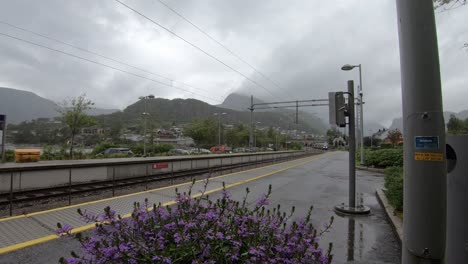 VY-passenger-train-arriving-at-Stanghelle-station-in-rainy-grey-weather---Static-wide-angle-from-platform-area-looking-at-front-of-train-when-arriving