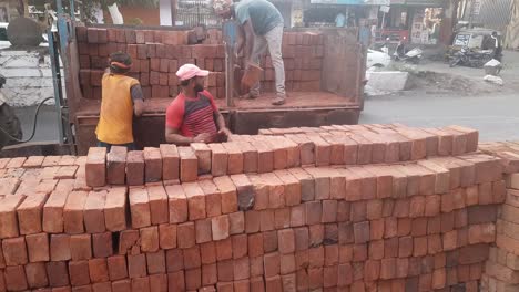 Un-Trabajo-Indio-Está-Descargando-Ladrillos-Rojos-Del-Carro-Del-Tractor-En-El-Sitio-De-Construcción