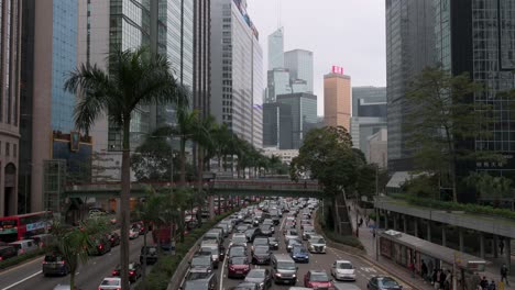 Der-Stau-Bahnt-Sich-Langsam-Seinen-Weg-Entlang-Einer-Straße,-Die-Von-Skylinen-Und-Finanzhochhäusern-In-Hongkong-Umgeben-Ist