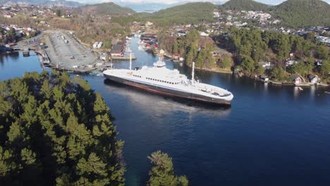 Flatoy-De-Ferry-Híbrido-Sale-Del-Puerto-De-Halhjem-A-Lo-Largo-De-La-Carretera-E39-En-La-Costa-Occidental-De-Noruega---Hermosa-Antena-De-Día-Soleado-Con-árboles-En-Primer-Plano-Ferry-En-Medio-Y-Muelle-En-Segundo-Plano