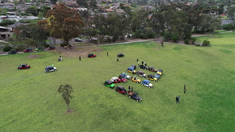 Moke-Owners-Association-50th-Anniversary-Convoy---Slow-pan-above-moke-vehicles-and-their-owners-preparing-a-word-sign