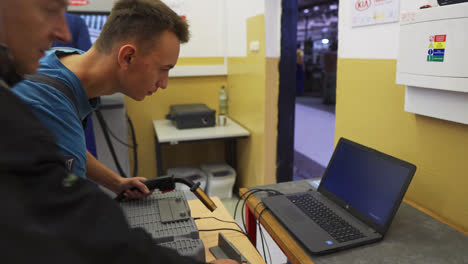 Estudiante-De-Soldadura-Mirando-Una-Computadora-Portátil-Conectada-A-Una-Máquina-De-Soldadura-Virtual-En-Una-Escuela-De-Oficios