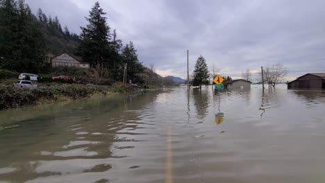 Low-forward-aerial-of-flooded-roads-by-houses-in-Abbotsford,-Canada