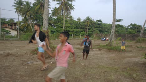 Man-playing-with-local-children-in-Weligama-village,-Sri-Lanka