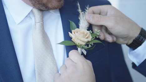 Trauzeuge-Befestigt-Boutonniere-Am-Revers-Des-Bräutigams,-Hochzeitsvorbereitung