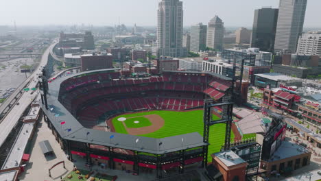 Aerial-Shot-of-Sports-Stadium,-Drone-Over-Bright-Green-Field-and-Empty-Bleachers