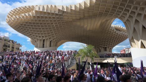 Los-Penitentes-Pasan-Por-La-Plaza-De-La-Encarnación-Bajo-El-Monumento-De-Las-Setas-Durante-Una-Procesión-Mientras-Celebran-La-Semana-Santa-En-Sevilla,-España