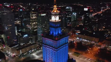 Vista-Aérea-Del-Palacio-Iluminado-De-La-Cultura-Y-La-Ciencia-En-Varsovia,-Polonia---Reversa,-Inclinación,-Tiro-Con-Drones