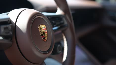 Cerrar-La-Insignia-De-Porsche-En-El-Volante-Del-Coche-Deportivo-Taycan