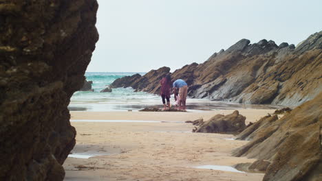 Momento-Genuino-De-La-Familia-étnica-Mientras-Los-Niños-Ven-Al-Padre-Llevar-Al-Hermanito-Para-Colgar-Los-Pies-En-Las-Olas-En-La-Arena-De-La-Playa---Acercamiento-Suave