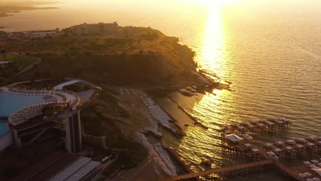 Eine-Drohnenaufnahme-Eines-Wunderschönen-Natürlichen-Strandblicks-Mit-Bäumen-Und-Luxushotels-Am-Strand-Bei-Sonnenuntergang