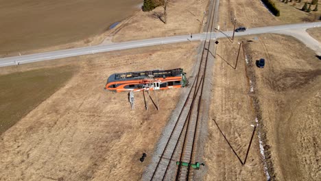 Drohnenaufnahme-Des-Elron-Zugunglücks-Neben-Der-Eisenbahn-Zwischen-Feld,-Autos-überqueren-Die-Eisenbahn-Im-Hintergrund