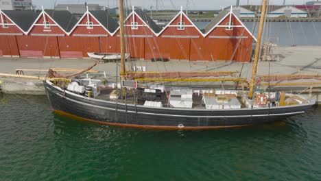 Aerial-view,-old-wooden-ship,-on-a-ship-deck-various-objects-and-buildings,-ship-moored-at-the-quays