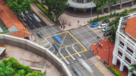 Traffic-moving-through-intersection-by-Carlton-Hotel,-Raffles-City-Mall,-Singapore