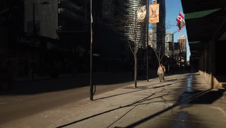 Plano-General-Diurno-Exterior-De-Una-Figura-Solitaria-Caminando-Hacia-El-Sur-Por-Una-Calle-Soleada-De-Yonge-En-Toronto